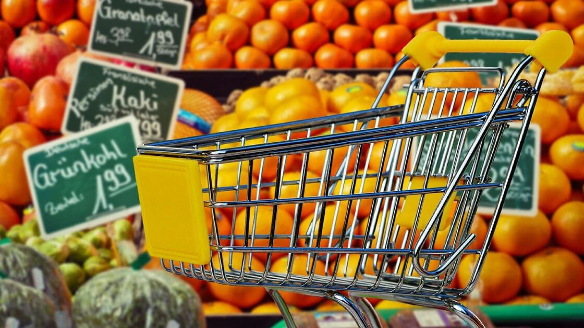 Einkaufswagen vor Gemüse- und Obstregal